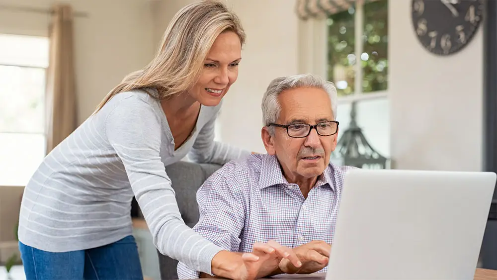 Lady helping gentleman on computer.